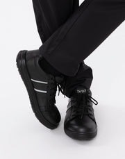 Black sneakers with white stripes worn with black pants