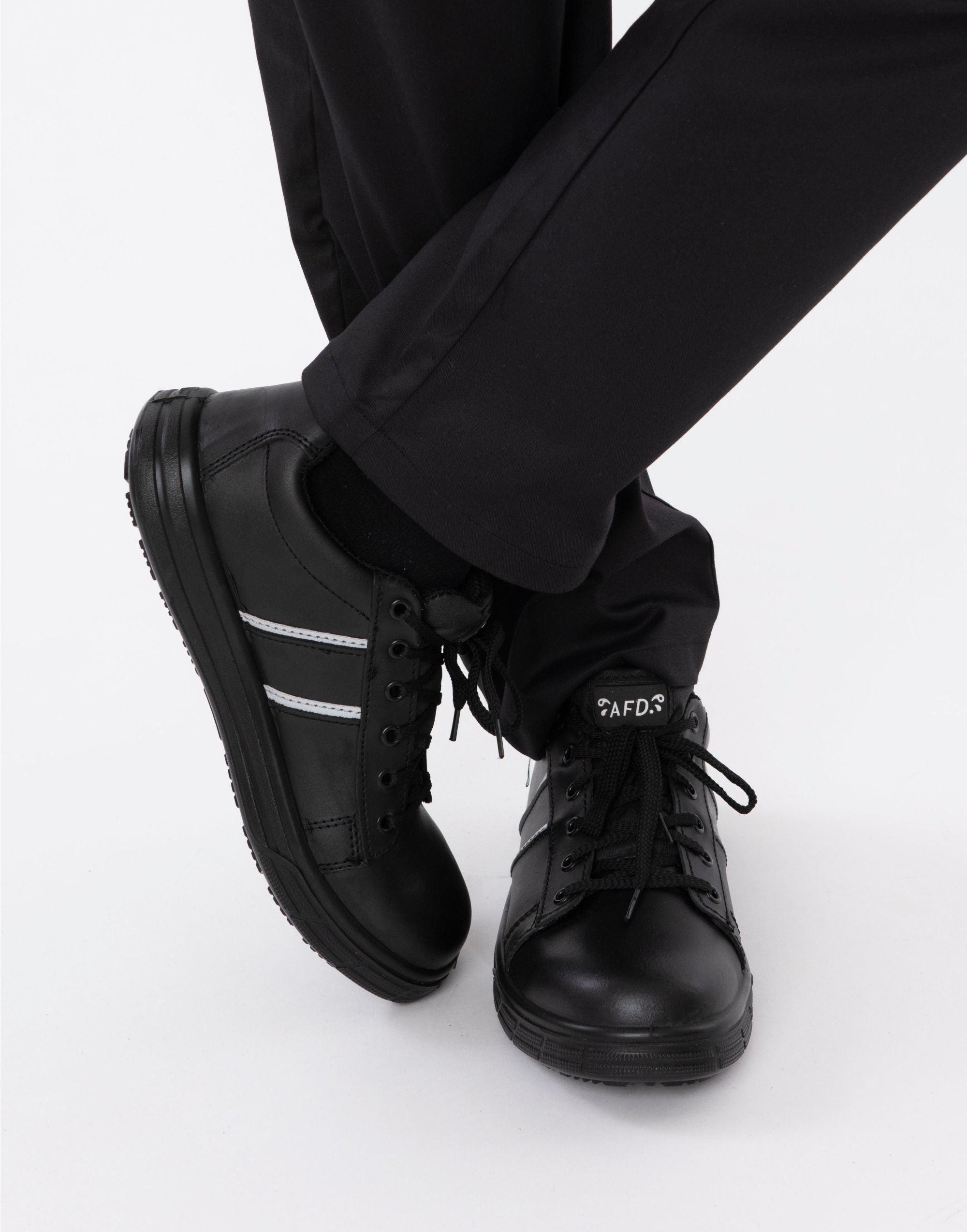 Black sneakers with white stripes worn with black pants